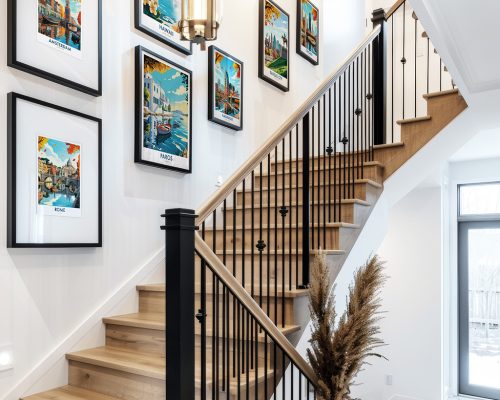 A staircase with framed art prints displayed on the wall, showcasing various colorful scenes.