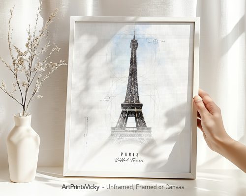 Art print of the Eiffel Tower in a white frame with a hand holding it.
