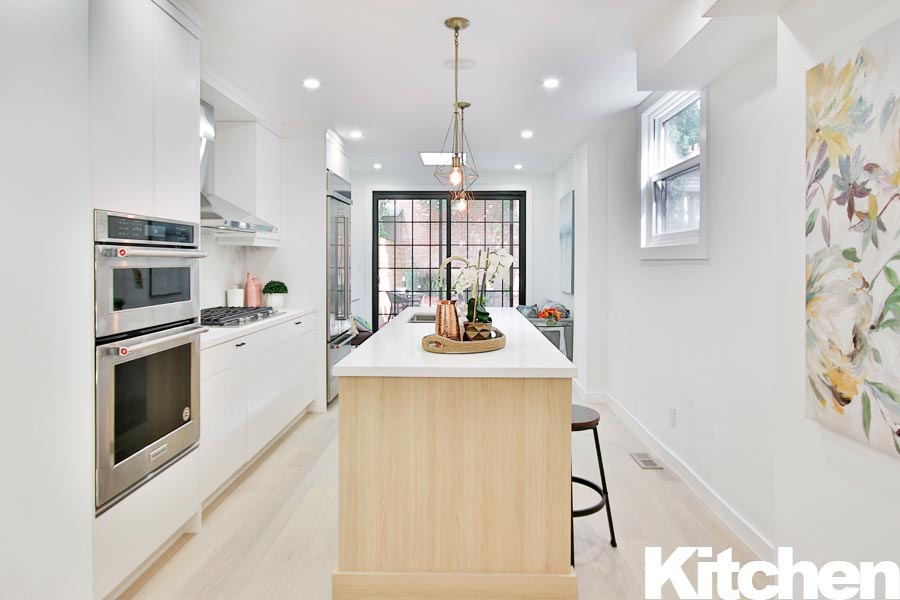 Contemporary kitchen featuring a central island, stainless steel appliances, and white cabinetry.