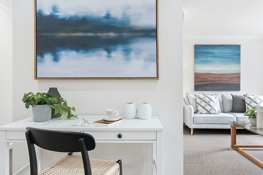 A modern interior featuring a desk with a chair, decorative plants, and framed artwork on the walls.