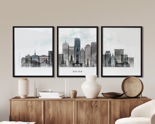 Three framed art prints of Boston's skyline displayed on a wooden surface.