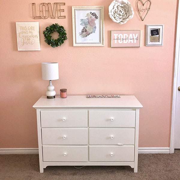 White dresser with six drawers and various decorative items on the wall above it.