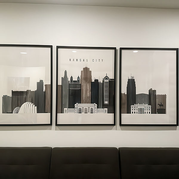 Three framed prints of Kansas City skyline in black and white displayed on a wall.