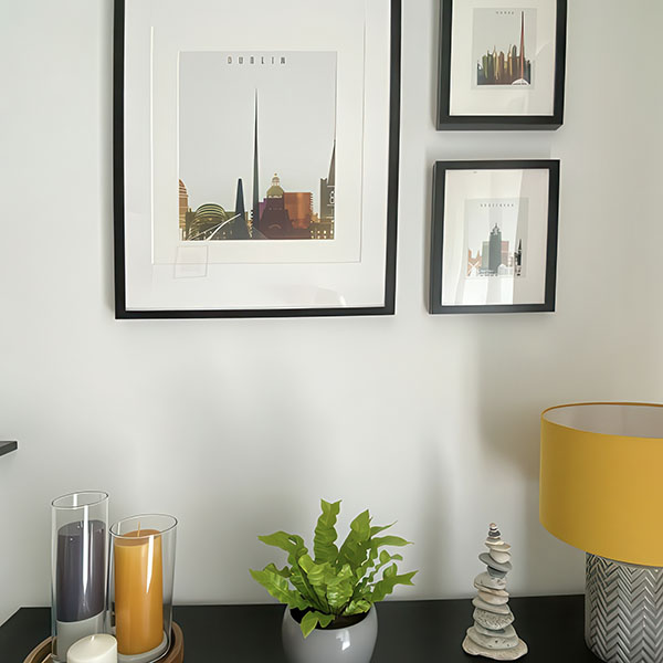 Framed prints of Dublin cityscape displayed on a wall with decorative items on a table.