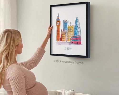 A woman touching a framed illustration of London featuring iconic buildings and a red bus.