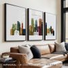Three framed art prints of the Minneapolis skyline in various colors displayed on a wall.