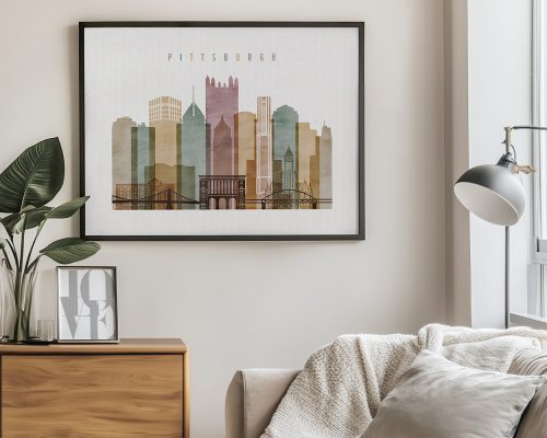 Framed artwork depicting a stylized skyline of Pittsburgh with various buildings and bridges.