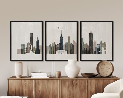 Three framed art prints of the New York City skyline displayed on a wall above a wooden sideboard.