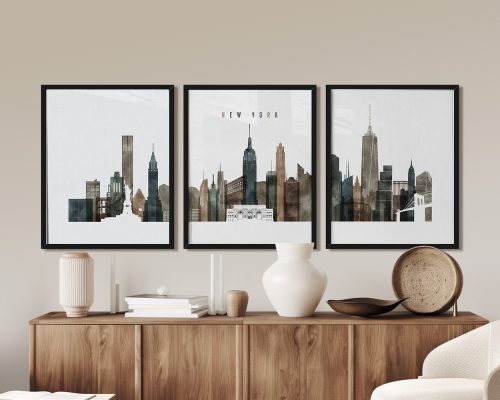 Three framed art prints of the New York City skyline displayed on a wooden surface.