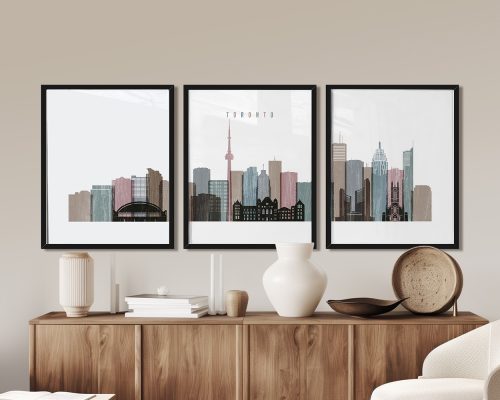 Three framed art prints of the Toronto skyline displayed on a wooden cabinet.
