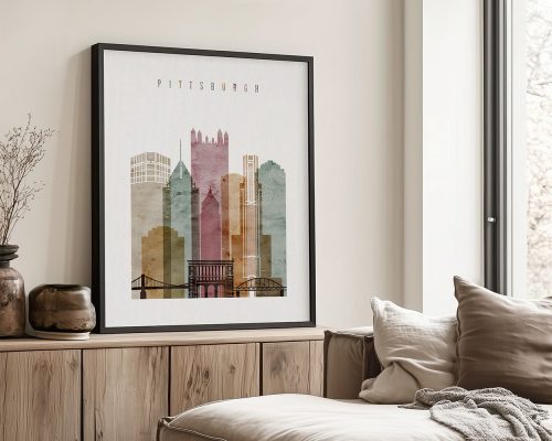 Framed artwork depicting a stylized cityscape of Pittsburgh with various buildings and a bridge.