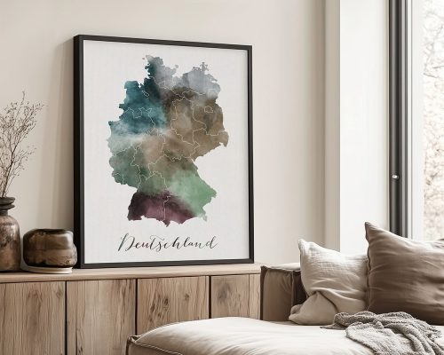 Watercolor map of Germany displayed in a black frame on a wooden surface.