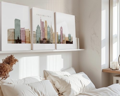 Three art prints of Philadelphia's skyline displayed above a bed in a neutral room.