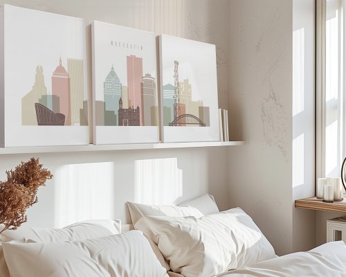 Three art prints of the Rochester city skyline displayed above a bed in a neutral-toned room.