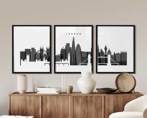 Three framed black and white cityscape prints of London displayed on a wooden sideboard.