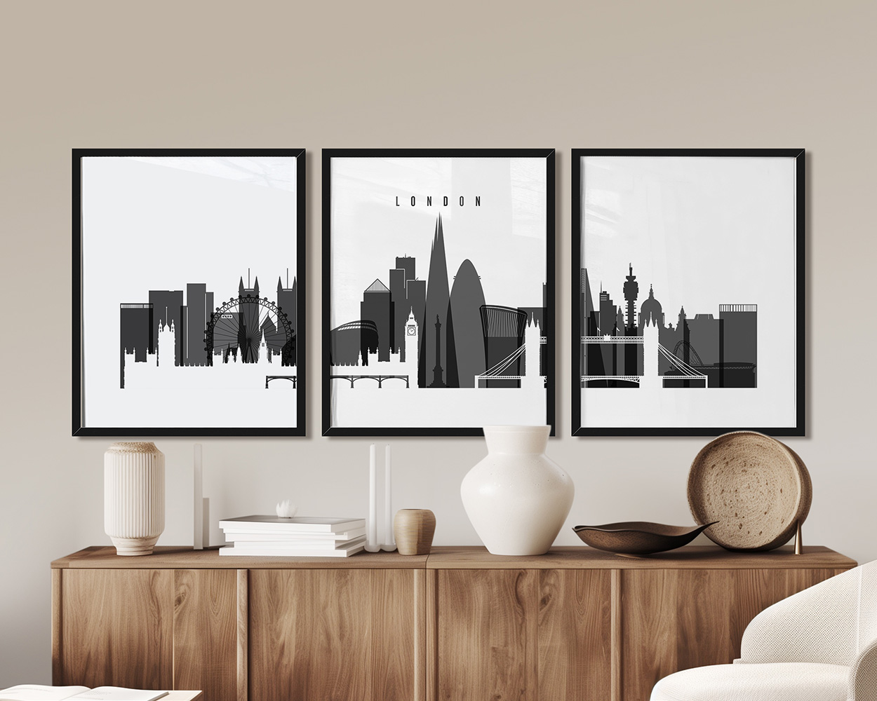 Three framed black and white cityscape prints of London displayed on a wooden sideboard.