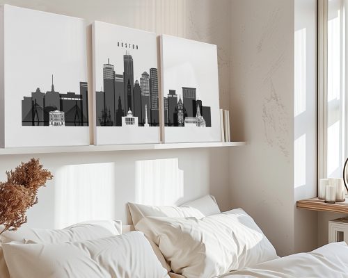 Three black and white art prints depicting the skyline of Boston on a shelf above a bed.