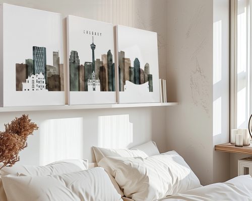 Three art prints of Calgary's skyline displayed above a bed in a modern interior.