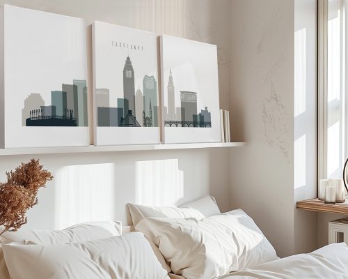 Three framed art prints of Cleveland's skyline displayed above a bed in a neutral room.