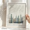 Framed artwork of a New York City map with skyline illustration in muted colors.
