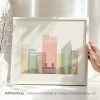 Art print of a stylized Oslo cityscape in pastel colors with a hand holding the frame.