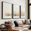 Three framed art prints of Paris landmarks displayed on a wall above a sofa.