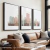 Three framed art prints depicting a stylized city skyline in muted colors.