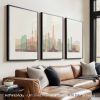 Three framed cityscape artworks displayed on a wall above a couch in neutral tones.