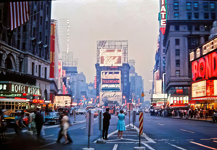 Historic view of Times Square in the 1960s with neon signs and vintage cars on the street.