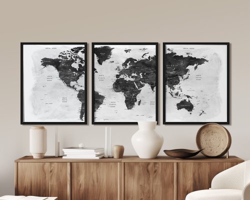 Three framed black and white world maps displayed on a wooden surface.